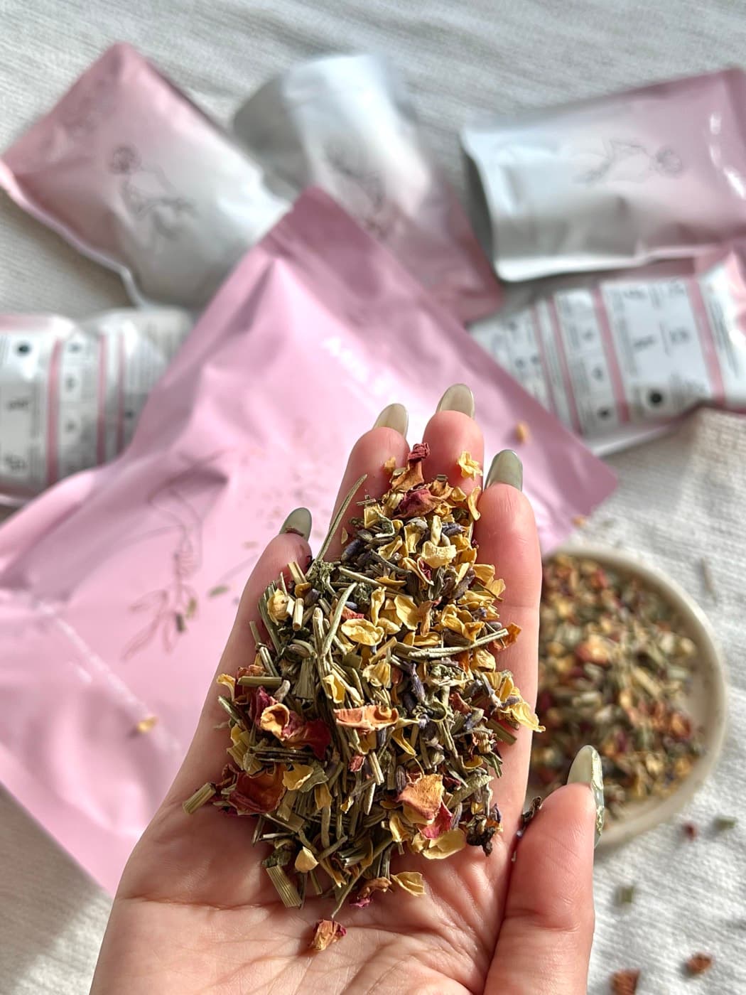 Loose steaming herbs held in a hand above a bowl